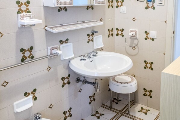 A bathroom with a white sink, a mirror, and a toilet. There are two towel racks and a small shelf above the sink. - M224 - Marcelli, three-room apartment with garden 150m from the sea (Marcelli)