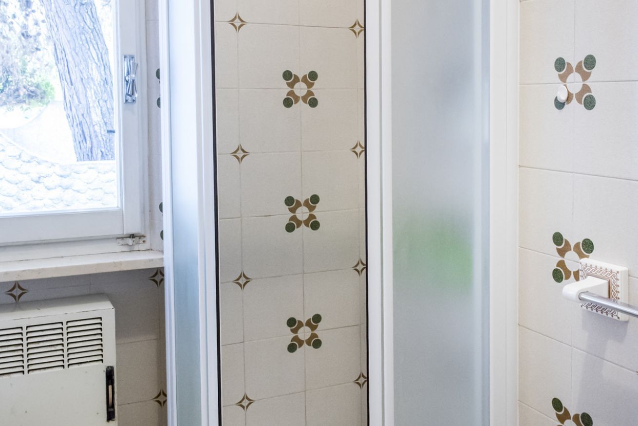 A bathroom with patterned tiles, a window, and a radiator.