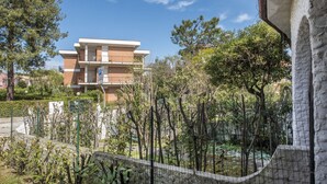 A multi-story building with a parking sign, surrounded by trees and a fence. - M224 - Marcelli, three-room apartment with garden 150m from the sea (Marcelli)