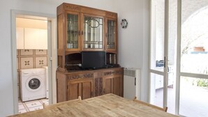 A kitchen with a wooden cabinet, a washing machine, and a table. - M224 - Marcelli, three-room apartment with garden 150m from the sea (Marcelli)