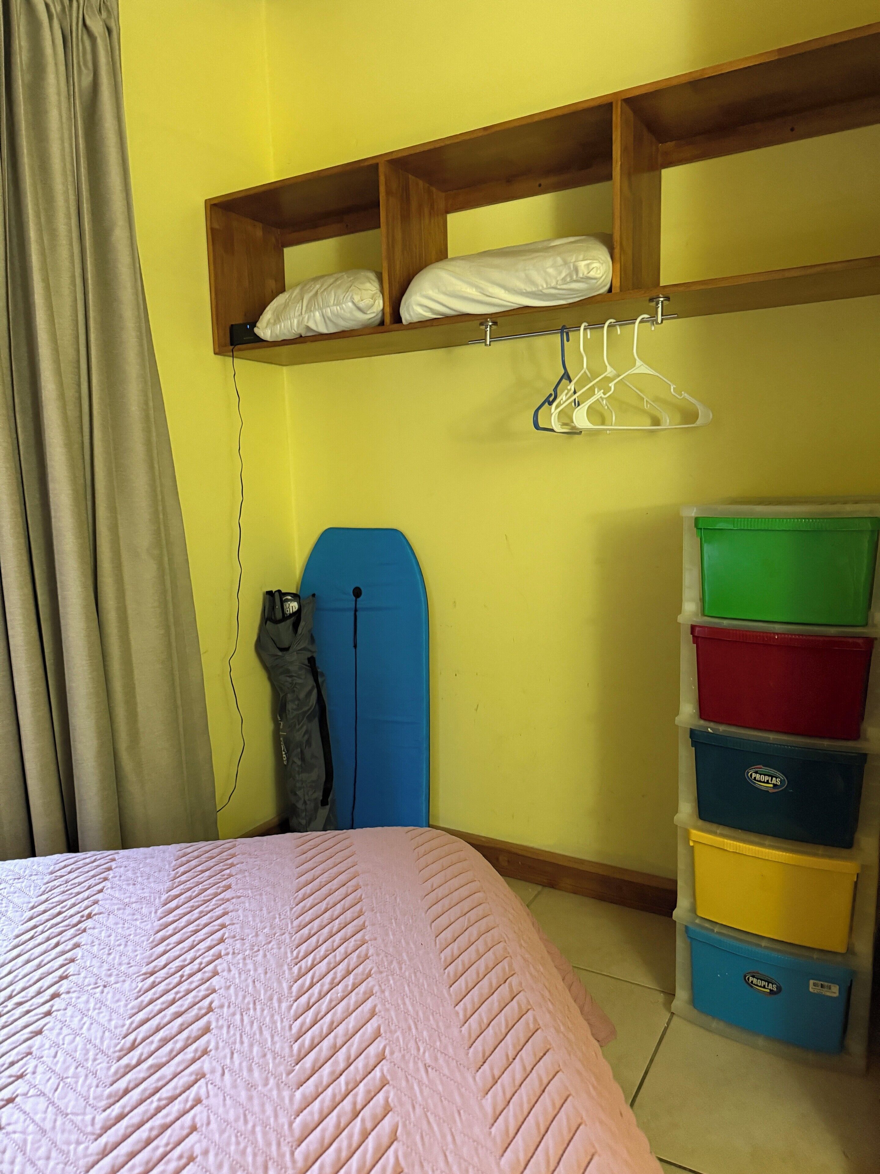 A bedroom with a bed, a wardrobe, and a set of storage bins.