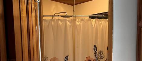 A bathroom with a shower curtain featuring a floral pattern, wooden doors, and a tiled floor.