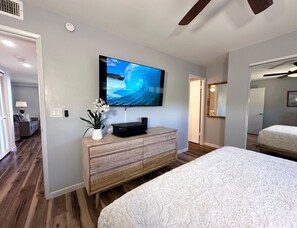 Un dormitorio con una cama, un aparador de madera, un televisor de pantalla plana y una planta en maceta.