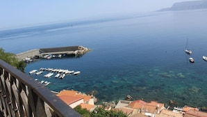 A coastal marina with boats docked, clear water, and buildings in the background. - Sea Side Rooms (Scilla)
