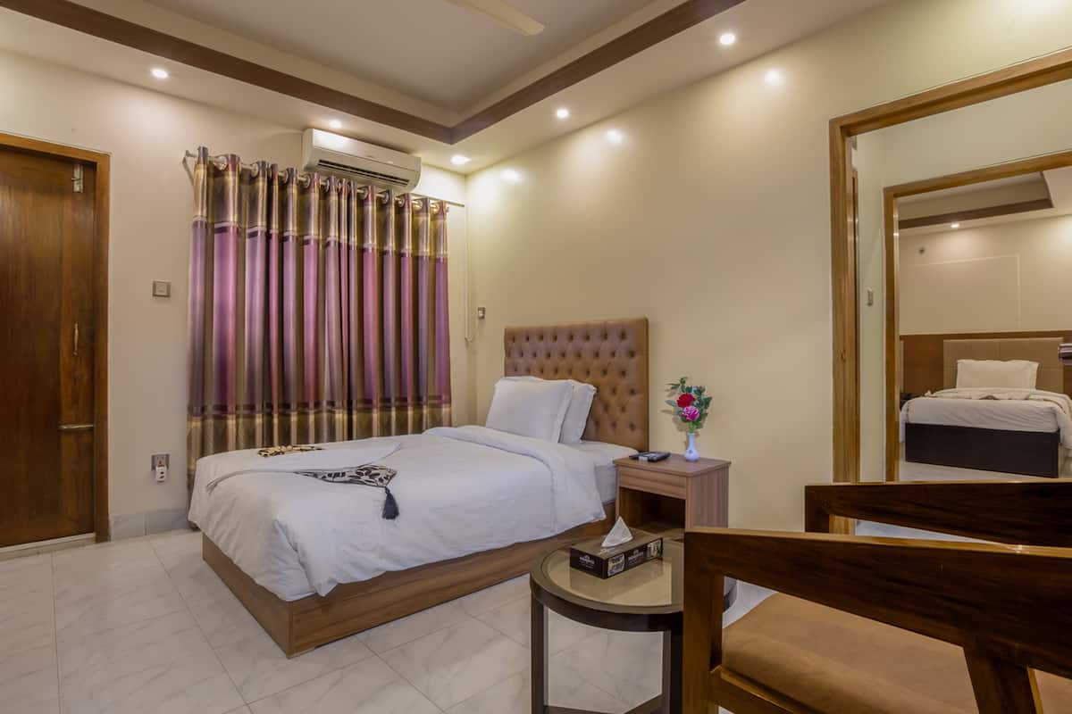A hotel room with a large bed, a bedside table with a vase of flowers, and a wooden chair.