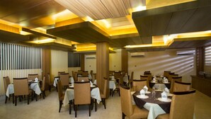 A restaurant with multiple tables and chairs, wooden ceiling beams, and air conditioning units. - Memento International (Dhaka)