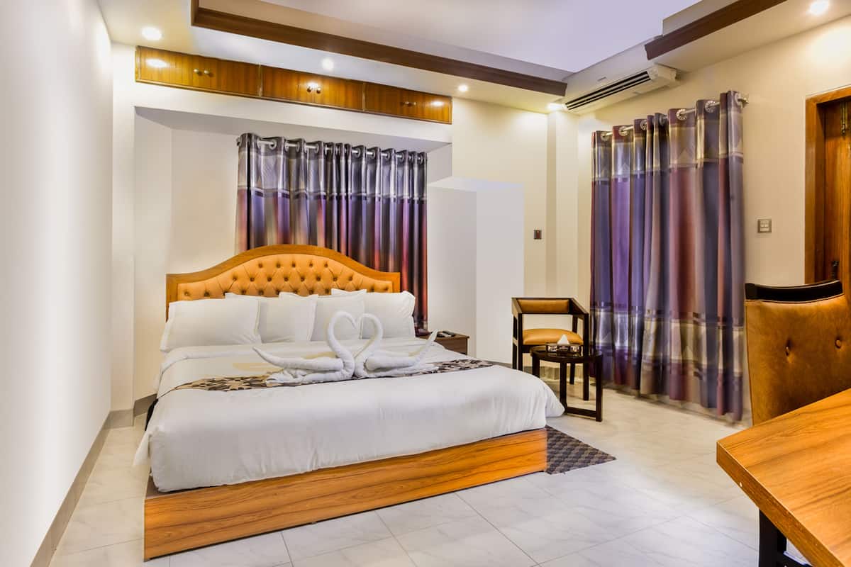 A neatly arranged bedroom with a large bed, a wooden headboard, and a bedside table.