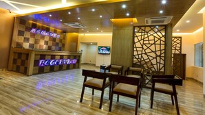 A reception area with a checkered wooden counter, a reception desk, and a seating area with chairs. - Memento International (Dhaka)