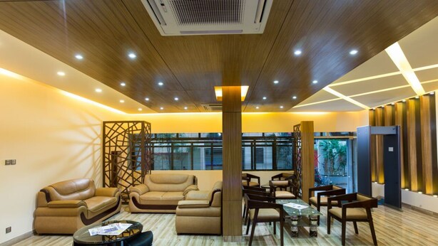 A modern lobby with leather sofas, a glass coffee table, and wooden accents. - Memento International (Dhaka)