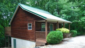 Eine Blockhütte mit Veranda, einer Tür und einem kleinen Fenster.