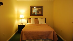 Ein Hotelzimmer mit Bett, Nachttisch mit Lampe und einem gerahmten Bild an der Wand.