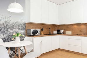 Una cocina moderna con armarios blancos, encimera de madera y una mesa de comedor blanca con sillas.