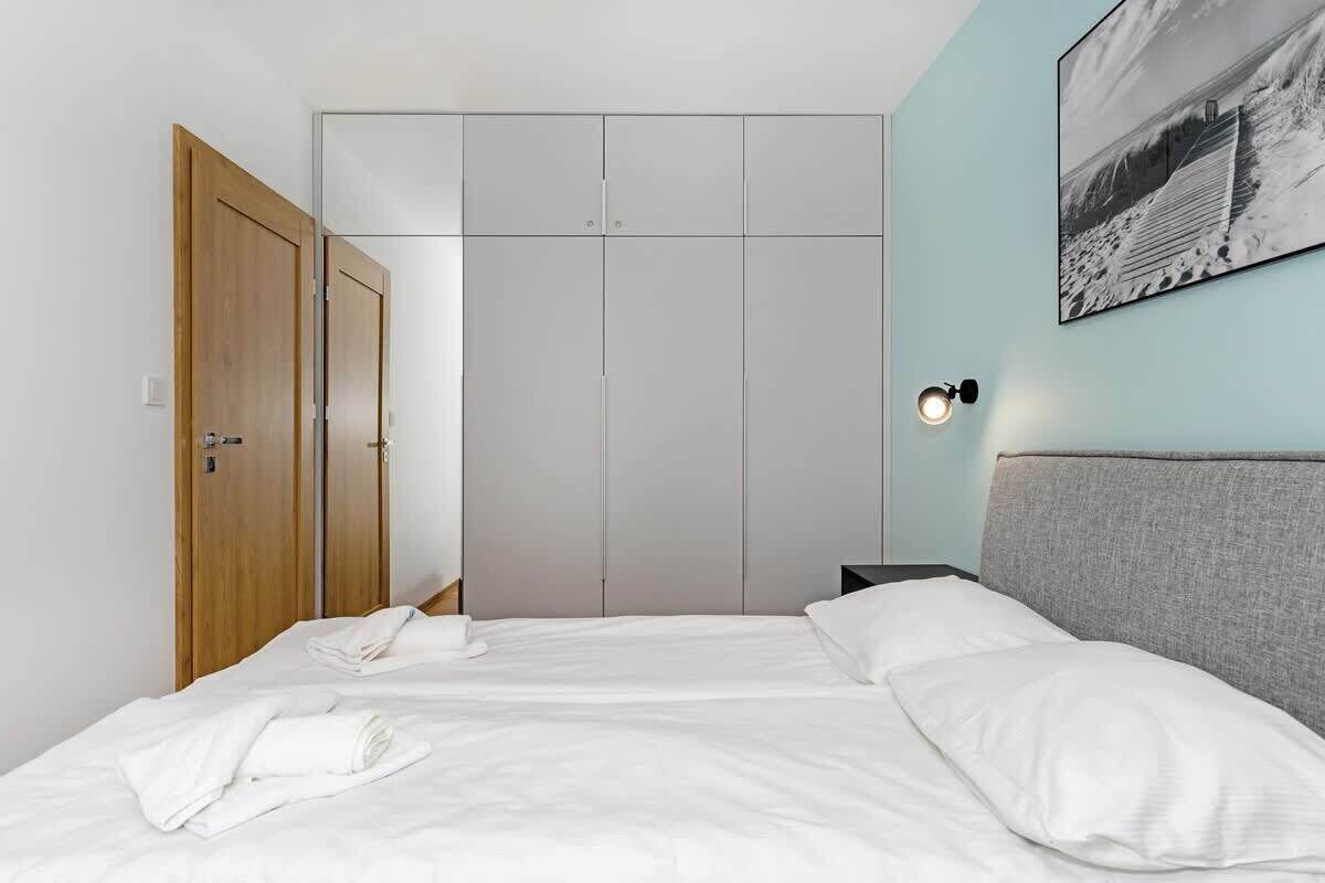 A hotel room with a bed, a wardrobe, and a wall-mounted light fixture.
