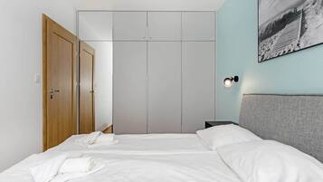 A hotel room with a bed, a wardrobe, and a wall-mounted light fixture.