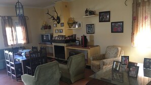 A living room with a fireplace, a television, and a dining area with chairs and a table. - "Chalet with Pool" (Montellano)