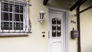 Eine weiße Tür mit Fenster und Briefkasten an der Wand.