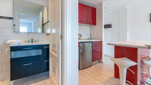 A modern kitchen with a built-in dishwasher, a red and white color scheme, and a white bar stool. - Los Tajinastes 1A034 (Playa de Las Americas)