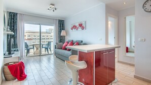 A modern living room with a sofa, chairs, a dining table, and a kitchen area with a bar counter. - Los Tajinastes 1A034 (Playa de Las Americas)