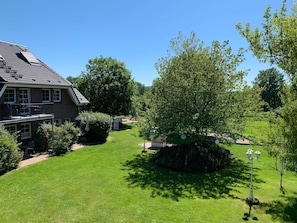 A house with a balcony, a well-maintained lawn, and a large tree in the yard.
