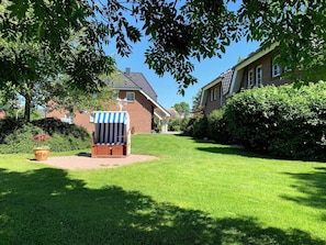 A well-maintained lawn with a wooden deck chair and a potted plant.