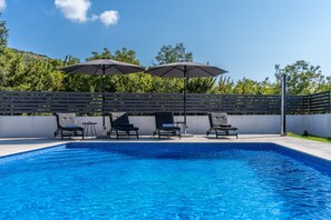 Een buitenzwembad en ligstoelen