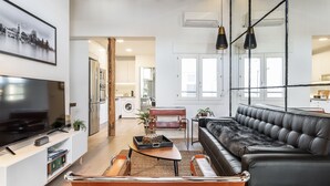 A modern living room with a large flat-screen TV, leather sofa, and a coffee table.