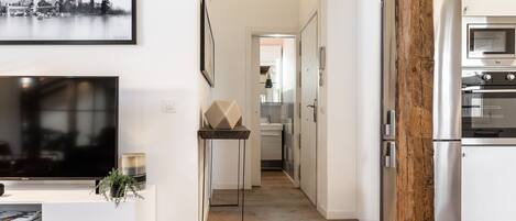 Une cuisine moderne dotée d’appareils électroménagers en acier inoxydable, d’une poutre en bois et d’un tableau représentant un paysage urbain accroché au mur.