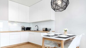 Una cocina moderna con armarios blancos, una encimera de madera y una zona de comedor con mesa y sillas blancas.