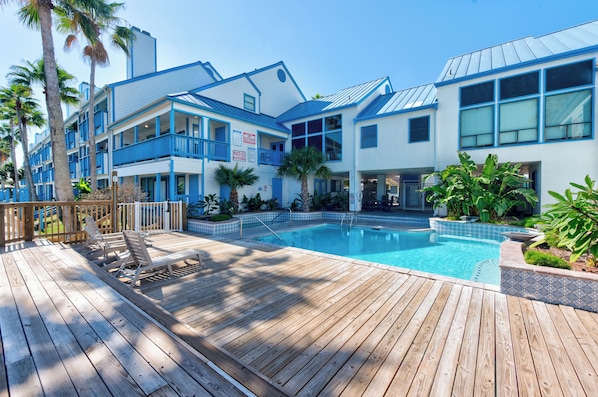 Un hôtel doté d’une piscine, d’une terrasse en bois et de balcons.