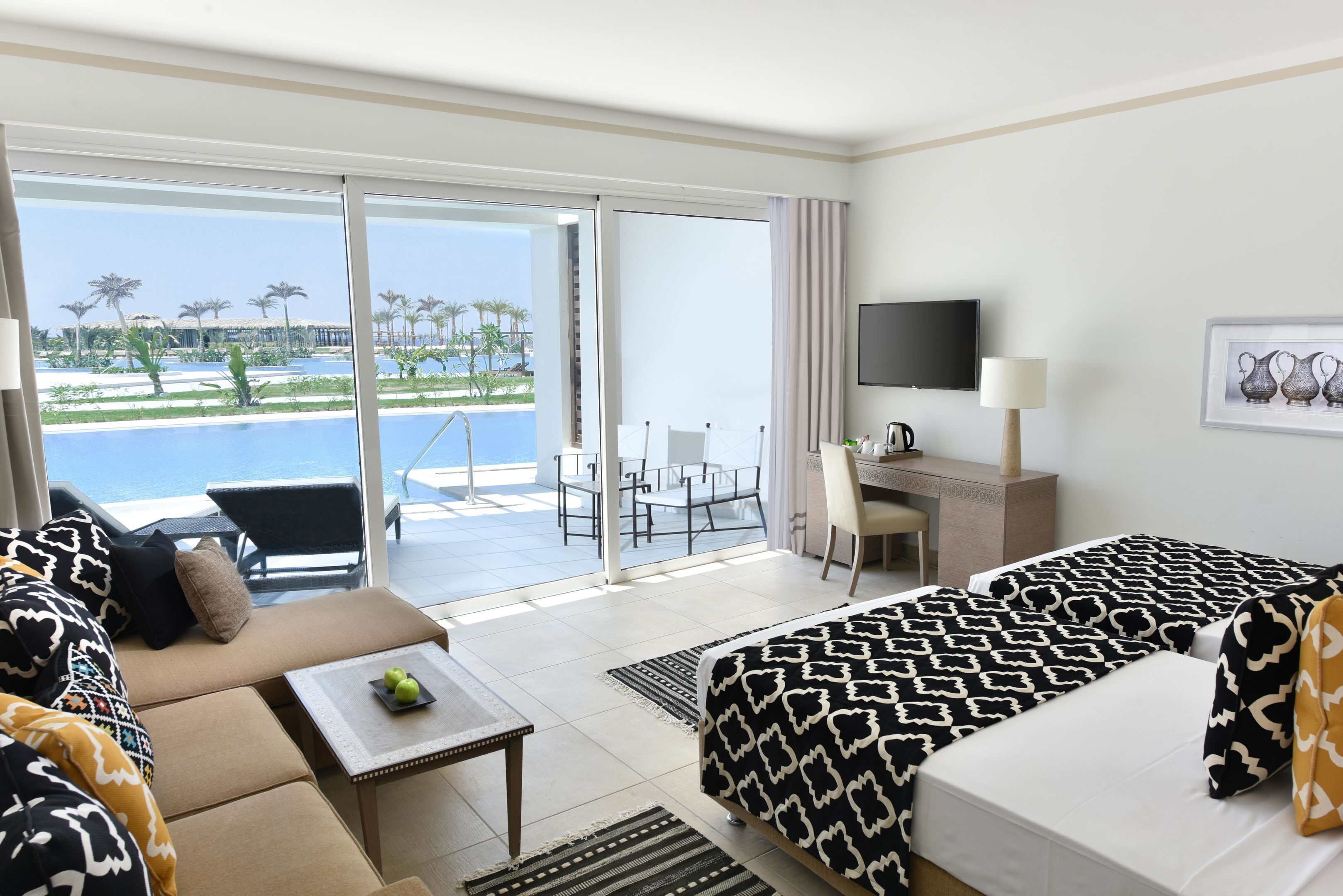 Une chambre d’hôtel avec un balcon, un lit, un canapé, un bureau et une télévision.
