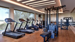 Une salle de sport moderne équipée de tapis de course, de vélos elliptiques et de matériel de musculation.