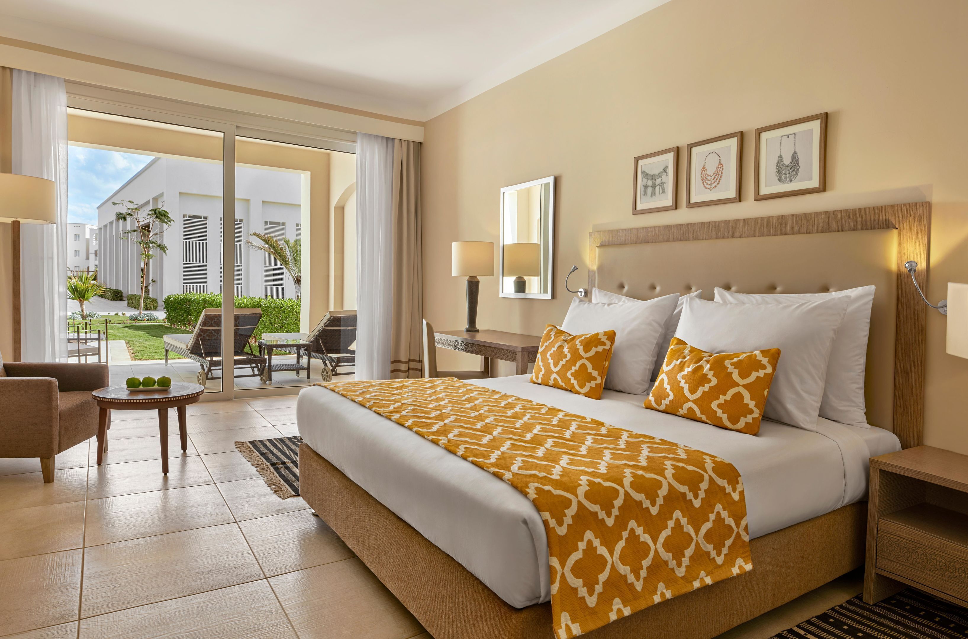 A hotel room with a large bed, a desk, a chair, and a view of the outdoor area.