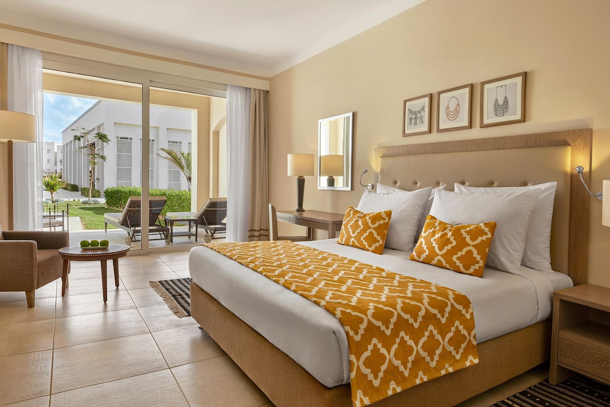Une chambre d’hôtel avec un grand lit, un bureau, une chaise et une vue sur l’espace extérieur.