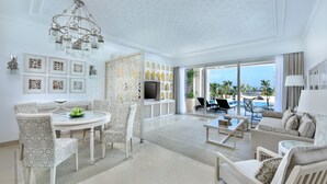 Un vaste salon comprenant un coin repas, un lustre et une vue sur l’océan.