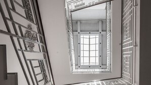 Eine Treppe mit aufwendiger Metallreling führt zu einem Raum mit einem großen Fenster.