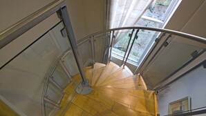 Eine Wendeltreppe mit Metallgeländern und Holzstufen, die zu einer Aussichtsplattform mit Blick auf Grünflächen führt.