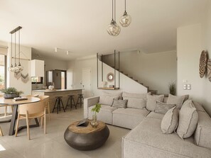 A modern living room with a sofa, coffee table, and dining area with chairs and a table.