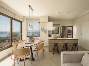 Una cocina moderna con una isla grande, taburetes de bar y un comedor con una mesa redonda y sillas.