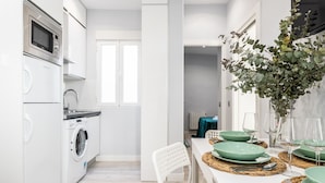 Une cuisine moderne équipée d’un lave-linge, d’un four à micro-ondes et d’un coin repas avec une table mise pour deux personnes.