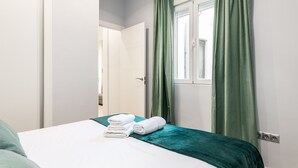 Une chambre d’hôtel avec un lit, des rideaux verts et une fenêtre.