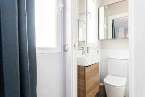 A modern bathroom with a white sink, wooden cabinet, and a white toilet.