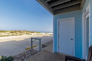 Un bâtiment situé au bord de la plage, avec une porte, une petite table et un banc.