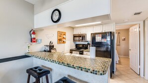 A modern kitchen with a large island, stainless steel appliances, and a clock on the wall. - Dog-Friendly Beachside Retreat | Patio, Pool & Hot Tub (Corpus Christi)