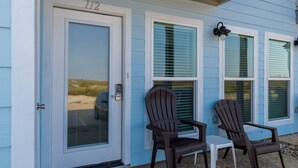 A house with a number 112 on the door, two Adirondack chairs, and a small table outside. - Dog-Friendly Beachside Retreat | Patio, Pool & Hot Tub (Corpus Christi)