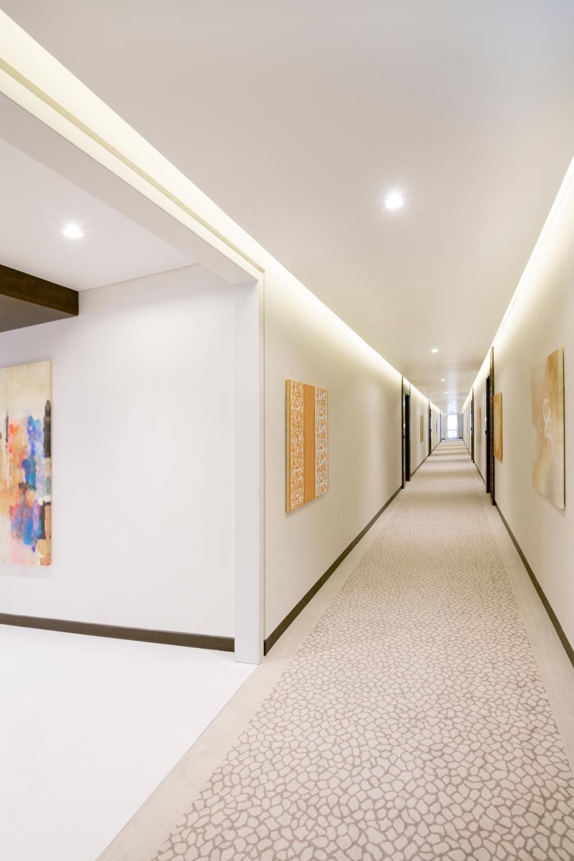 A long, well-lit hallway with patterned flooring and artwork on the walls.