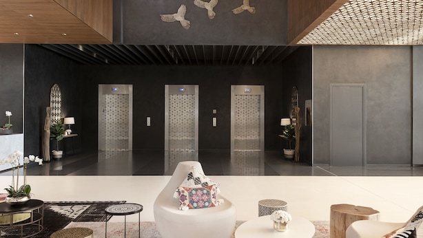 A spacious lobby with a high ceiling, modern furniture, and decorative ceiling lights.