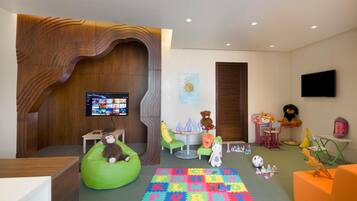 A children's play area with a large alphabet puzzle mat, bean bag chairs, and various toys.