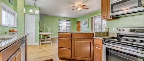 A kitchen with wooden cabinets, a granite countertop, a built-in oven, and a ceiling fan.