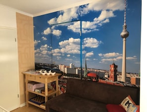 Panoramic city views adorn the wall, complemented by a comfortable sofa and a stylish shelf.