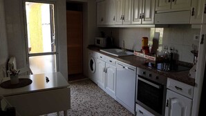 A compact kitchen with white cabinets, a washing machine, a microwave, and a sink.